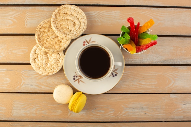 Eine Tasse Kaffee von oben heiß und stark mit französischen Macarons und Marmelade auf dem cremefarbenen rustikalen Schreibtisch trinken Kaffee Foto starken Keks