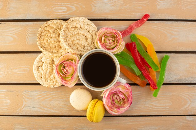 Eine Tasse Kaffee von oben heiß und stark mit französischen Macarons und Marmelade auf dem cremefarbenen rustikalen Schreibtisch trinken Kaffee Foto süßer Keks