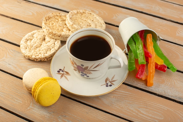 Eine Tasse Kaffee von oben heiß und stark mit französischen Macarons und Marmelade auf dem cremefarbenen rustikalen Tisch trinken Kaffee Foto stark