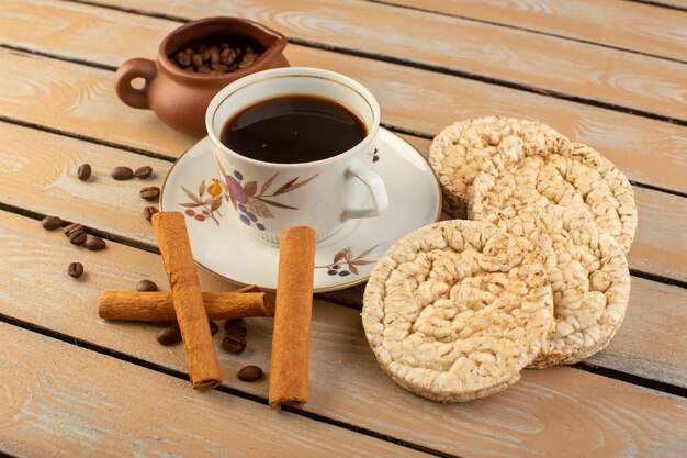 Eine Tasse Kaffee von oben heiß und stark mit frischen braunen Kaffeesamen und Crackern auf dem cremefarbenen rustikalen Schreibtischkaffee-Samengetränk-Fotokorn