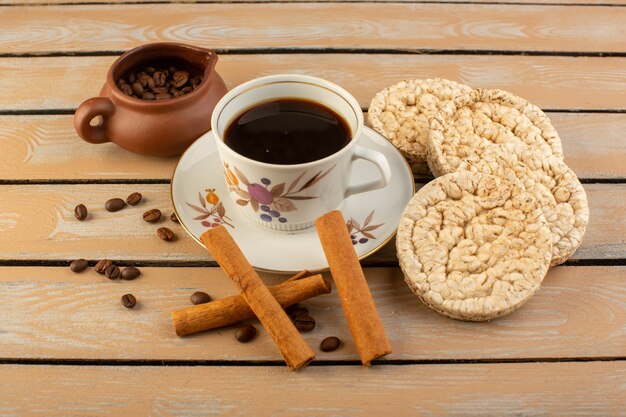 Eine Tasse Kaffee von oben heiß und stark mit frischen braunen Kaffeesamen Zimt und Cracker auf der Creme rustikalen Schreibtisch Kaffeesamen Getränk Fotokorn