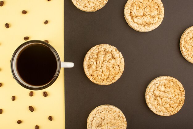 Eine Tasse Kaffee von oben mit braunen Kaffeesamen und runden Crackern