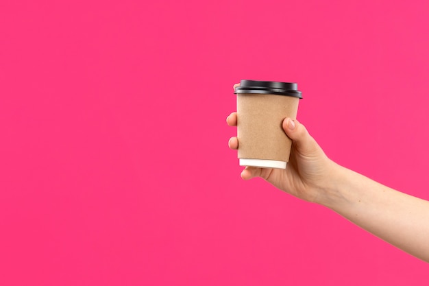 Eine Tasse Kaffeehand der Vorderansicht, die rosa Hintergrundfarbgetränk der männlichen männlichen Hand hält