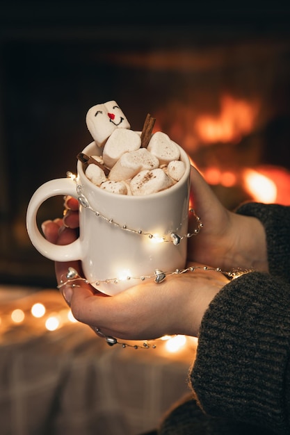 Kostenloses Foto eine tasse kakao mit marshmallows in weiblichen händen am kamin