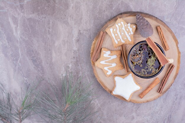 Eine Tasse Kräutertee mit Lebkuchen auf einem Holzbrett