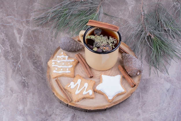 Eine Tasse Kräutertee mit sternförmigen Lebkuchen auf einem Holzbrett