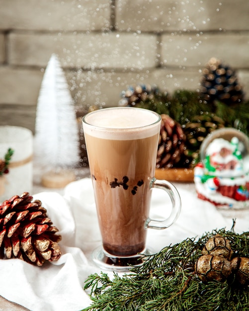 Eine Tasse Latte neben Weihnachtsschmuck