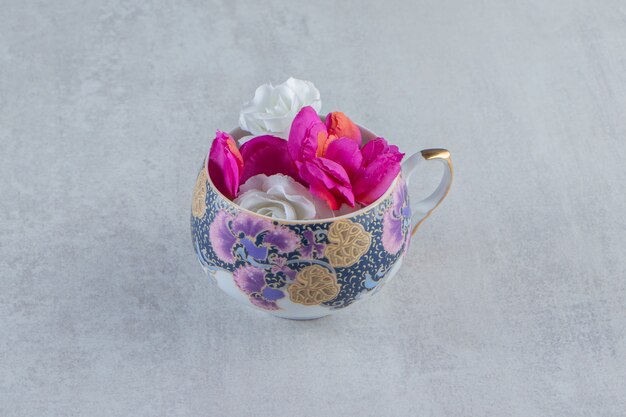 Eine Tasse lila und weiße Blumen auf dem weißen Tisch.
