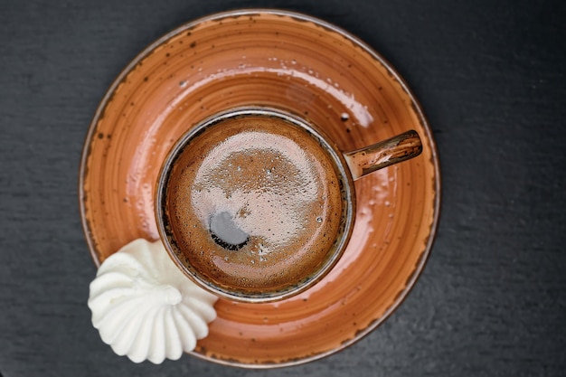 Eine Tasse mit starkem türkischen Kaffee auf einem schwarzen alten Tisch neben der Bizet-Draufsicht