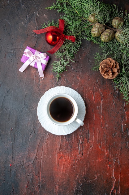 Eine Tasse Schwarztee-Tannenzweige Dekorationszubehör und Geschenk auf dunklem Hintergrund