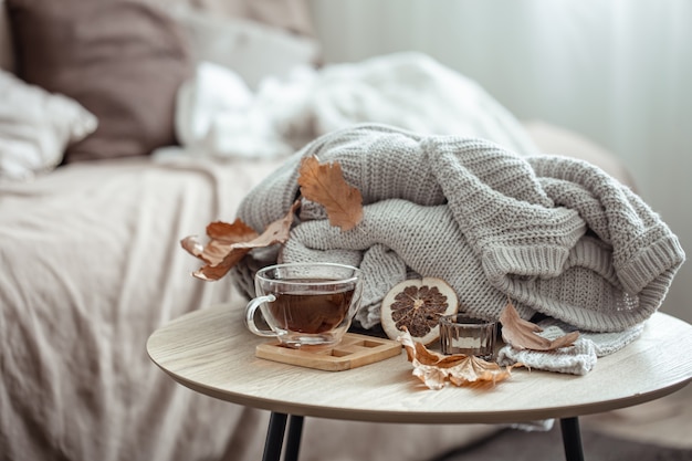 Kostenloses Foto eine tasse tee, ein gestricktes element und trockenes herbstlaub auf unscharfem hintergrund.