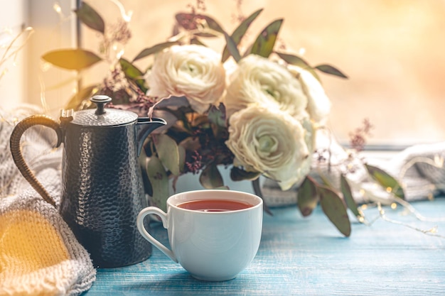 Kostenloses Foto eine tasse tee, ein kessel und blumen am fenster