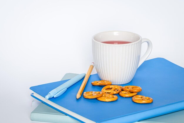 Eine Tasse Tee und Notizbücher auf einem weißen Hintergrund lokalisierten Kopienraum
