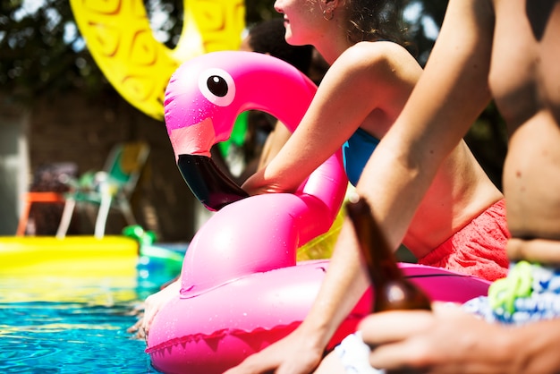Eine verschiedene Gruppe Freunde, die Sommerzeit am Pool mit aufblasbaren Hin- und Herbewegungen genießen