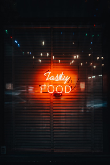 Eine vertikale Aufnahme von hellen Neonlichtern, die "Tasty Food" buchstabieren