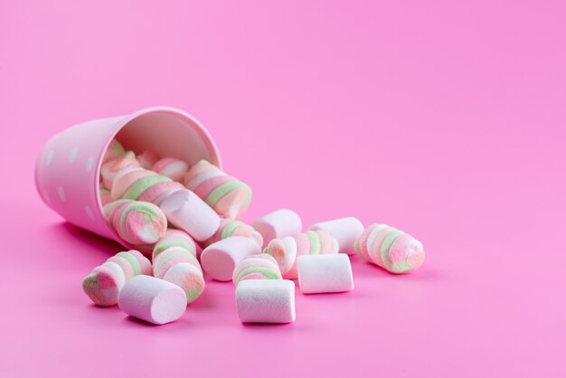 Eine Vorderansicht, die Marshmallow kaut, süß und köstlich auf rosa, süßer Zuckerfarbe