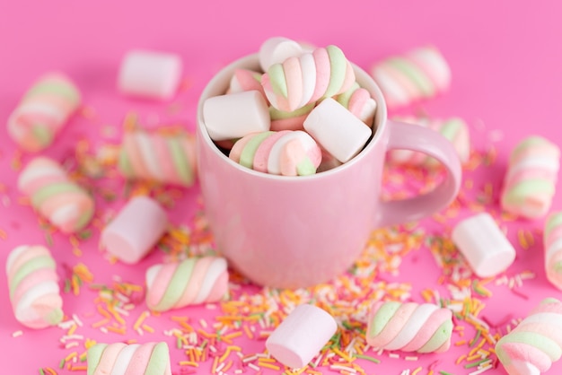 Eine Vorderansicht, die Marshmallows innerhalb von Rosa, Tasse und alles auf rosa, Farbe Regenbogenzuckerkonfiguration kaut