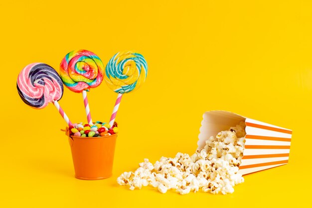 Eine Vorderansicht farbige Lutscher mit bunten Bonbons und Popcorn auf Gelb