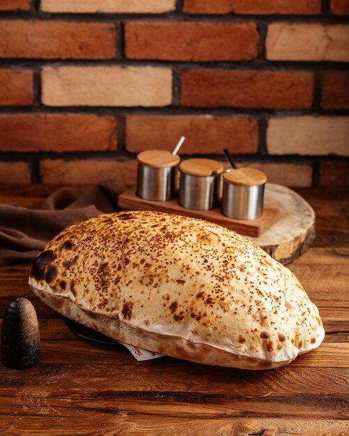 Eine Vorderansicht gebackenes Brot heiß und frisch auf dem braunen Holzschreibtisch