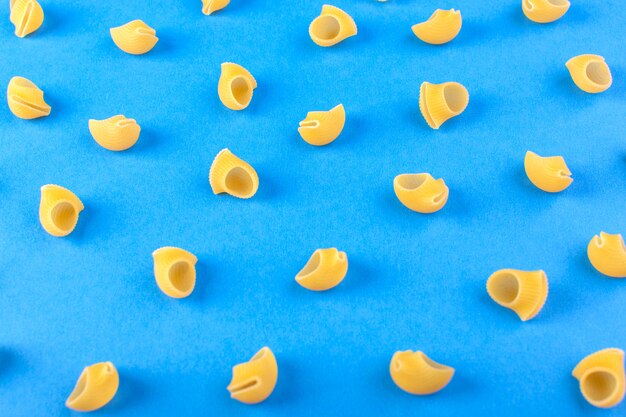 Eine Vorderansicht isolierte gelbe Nudeln wenig roh auf den blauen Hintergrundnahrungsmittelmahlzeit-Spaghetti-Nudeln