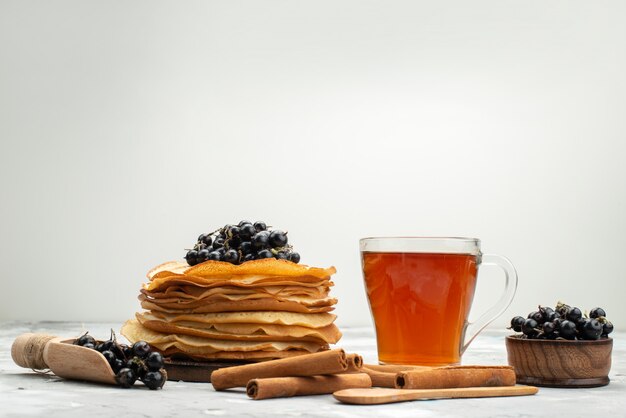 Eine Vorderansicht köstliche runde Pfannkuchen lecker und rund geformt mit Blaubeeren und Zimtpfannkuchengebäck, das Zucker kocht