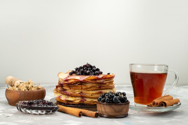 Eine Vorderansicht köstliche runde Pfannkuchen lecker und rund geformt mit Blaubeeren und Zimtpfannkuchengebäck