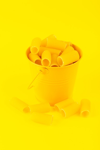 Eine Vorderansicht-Nudeln innerhalb des Korbs bildeten rohen inneren gelben Korb auf dem gelben Hintergrundmahlzeit-italienischen Spaghetti