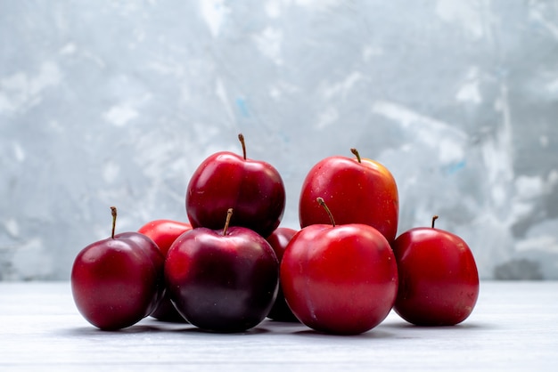 Eine Vorderansicht saure Pflaumen rot weich und saftig auf der weißen Hintergrundfrucht frische Farbe sauer