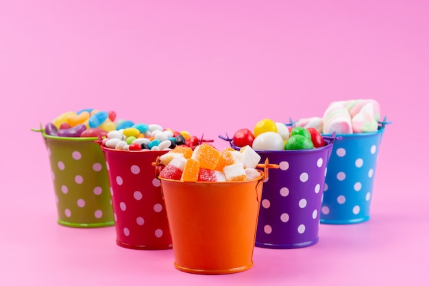 Eine Vorderansicht verschiedener Süßigkeiten wie z. B. Konfitüren Marmeladenbonbons in Körben auf rosa, zuckersüße Farbe