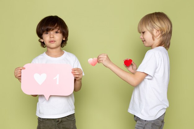 Eine Vorderansicht zweier Jungen, die in weißen T-Shirts auf dem steinfarbenen Raum entzückend sind