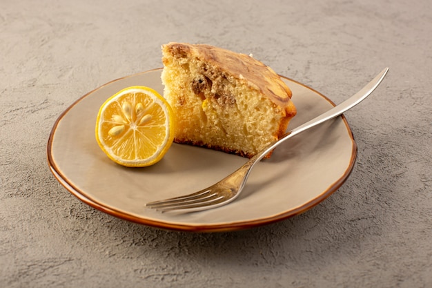 Eine vordere geschlossene Ansicht süßes Kuchenstück köstlicher leckerer Schokoladenkuchen, der in beige Platte mit Zitronenstück geschnitten wird