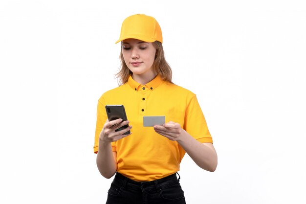 Eine weibliche weibliche Kurierarbeiterin der Vorderansicht lächelnd, während sie Informationen von der weißen Karte in das Telefon auf Weiß tippt