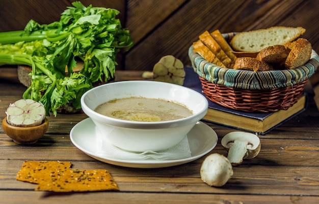 Kostenloses Foto eine weiße keramikschale pilzsuppe serviert mit knoblauchhandschuhen