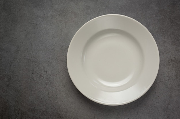 Eine weiße runde leere Platte auf dunkler Oberfläche