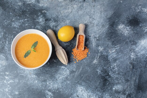 Eine weiße Schüssel Linsensuppe mit einer hölzernen Reibahle.