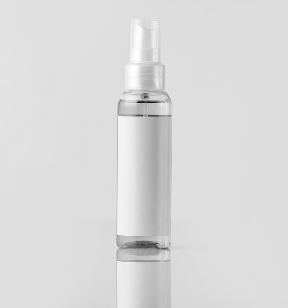 Eine weiße Sprühflasche der Vorderansicht lokalisiert auf dem braunen Schreibtisch