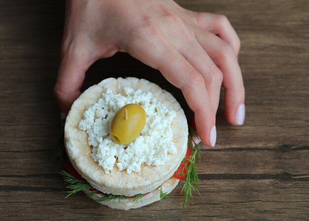 Einen glutenfreien Crackerburger zu einem Holztisch setzen.