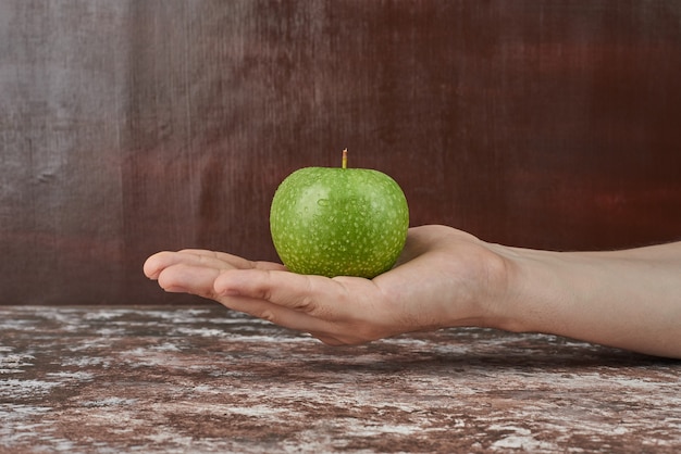 Einen grünen Apfel in der Hand halten.