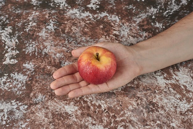 Einen roten Apfel in der Hand halten.