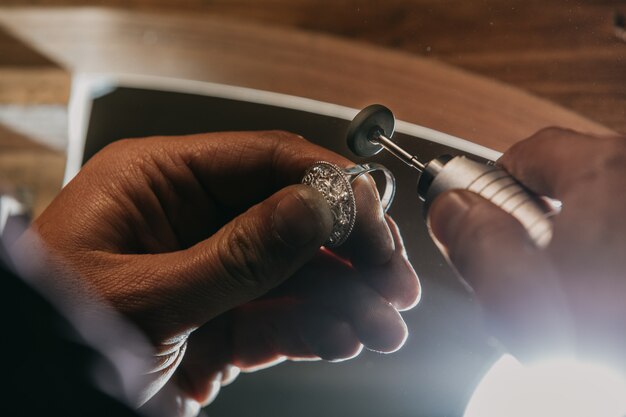 Einen silbernen Ring mit einem Gerät schälen