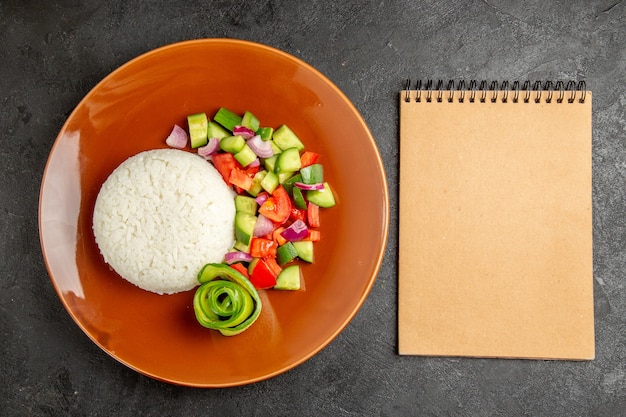 Einfache gesunde Mahlzeit und Notizbuch auf dunklem Hintergrund