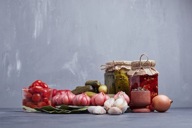 Eingelegte Gurken und Paprika im Glas mit Blatt-, Knoblauch-, Zwiebel- und Getreidepaprika.