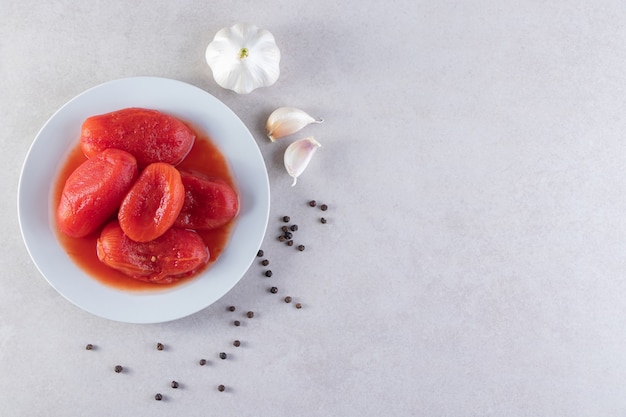 Eingelegtes Tomatengemüse mit frischen Knoblauch- und Pfefferkörnern.