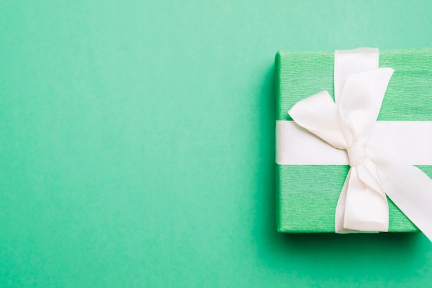 Eingewickeltes Geburtstagsgeschenk mit weißem Bandbogen auf grünem Hintergrund