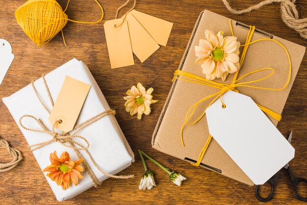 Eingewickeltes Geschenk gebunden mit Markenschnur und schöner Blume auf Holzoberfläche