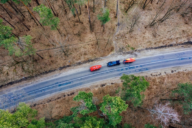 Kostenloses Foto einige autos mit kajaks auf dem dachgepäckträger, der auf die straße unter bäumen fährt