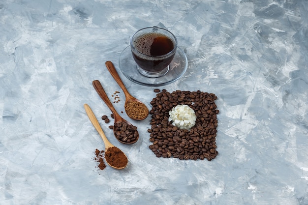Einige Kaffeebohnen, eine Tasse Kaffee mit Kaffeebohnen, Instantkaffee, Kaffeemehl in einem Holzlöffel