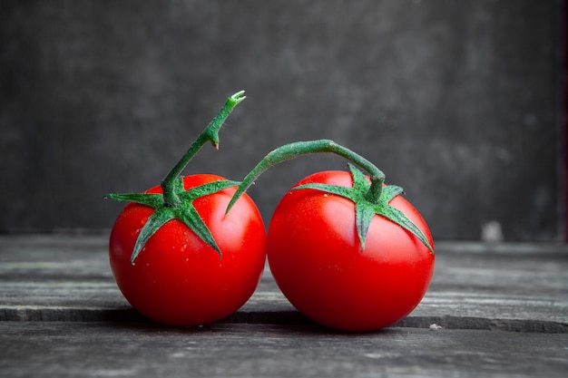 Einige Tomaten auf dunklem Holz und strukturiertem Hintergrund, Seitenansicht.