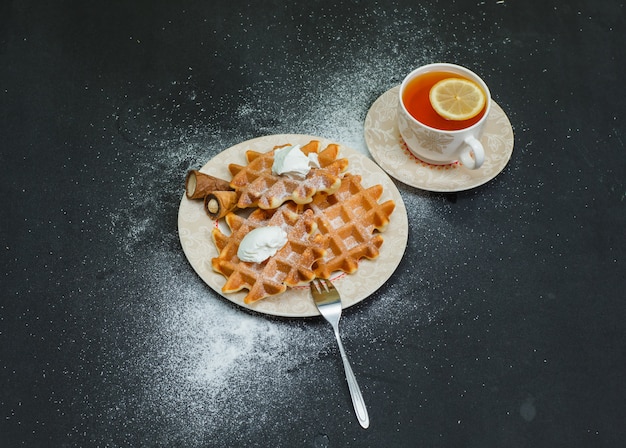 Kostenloses Foto einige waffeln mit tee in einem teller auf dunkler, hoher winkelansicht.