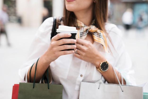 Einkaufenmädchen, das einen Kaffee trinkt